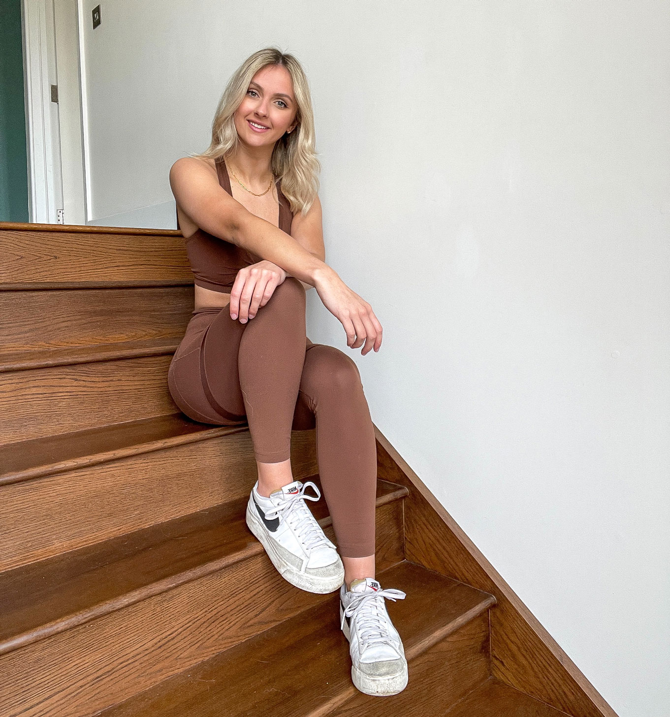 Coach Hannah Tucker sitting on stairs facing the camera and smiling with her hands on her knee